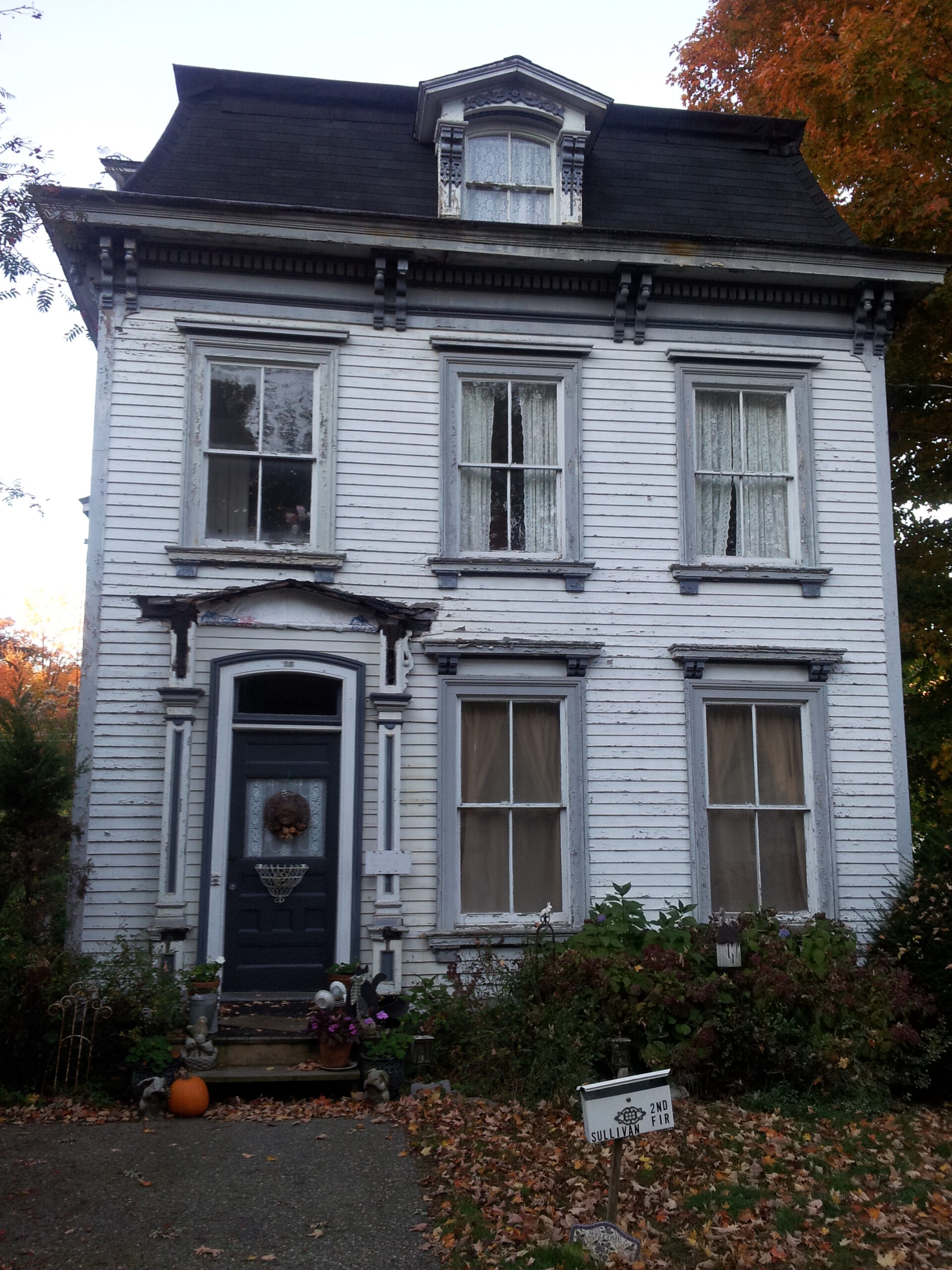 White house with deterioting siding and windows.